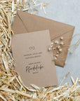 Kraftpapier Postkarte mit Kraftpapier Umschlag auf Stroh und grauem Untergrund