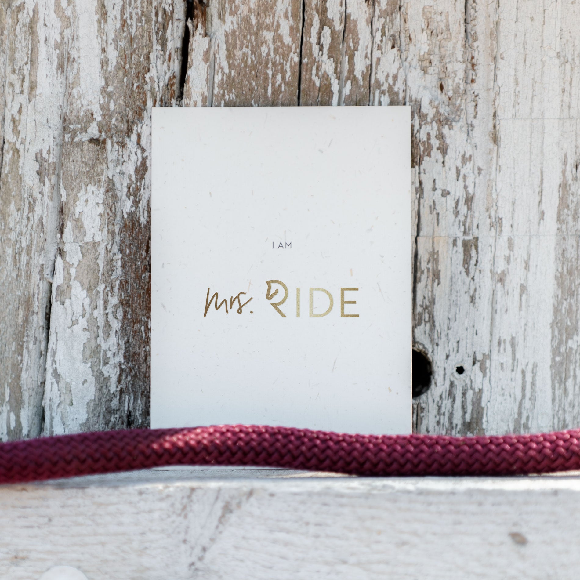 Postkarte aus Strohpapier mit Goldfolie vor hellem Holz 